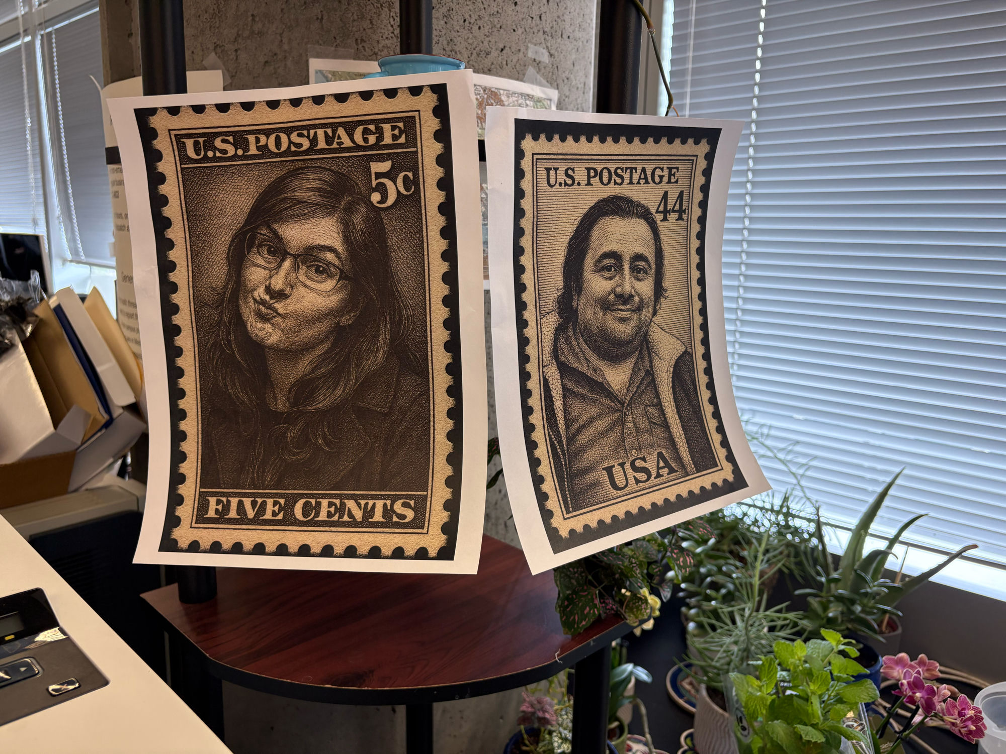 Two hand-drawn postage stamp portraits of Rachel Turn and Mohammad Ovais Aziz-Zanjani hanging in the office